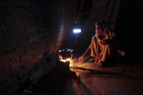 A woman cooks over a wood-burning fire under a battery-run emergency light during a power outage in a slum in Islamabad April 29, 2013. REUT A woman cooks over a wood-burning fire under a battery-run emergency light during a power outage in a slum in Islamabad April 29, 2013. REUT