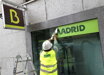 A worker removes a Caja Madrid signage to replace it with Bankia logos at a Bankia branch in Madrid May 20, 2013. REUTERS/Paul Hanna A worker removes a Caja Madrid signage to replace it with Bankia logos at a Bankia branch in Madrid May 20, 2013. REUTERS/Paul Hanna