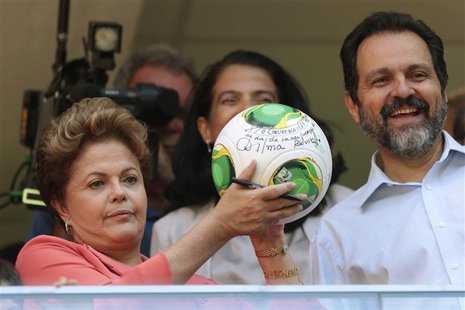 Brazil's President Dilma Rousseff (L) shows her autograph on a soccer ball as she stands beside Brasilia's Governor Agnelo Queiroz (R) durin Brazil's President Dilma Rousseff (L) shows her autograph on a soccer ball as she stands beside Brasilia's Governor Agnelo Queiroz (R) durin