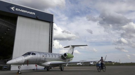 A worker rides a bicycle around the hangars next to a private jet at the Embraer headquarters in Sao Jose dos Campos, 100 km (62 miles) from A worker rides a bicycle around the hangars next to a private jet at the Embraer headquarters in Sao Jose dos Campos, 100 km (62 miles) from