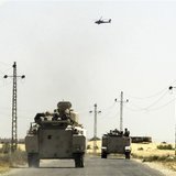 A helicopter flies overhead as soldiers in military vehicles proceed towards al-Jura district in El-Arish city from Sheikh Zuwaid, around 35 A helicopter flies overhead as soldiers in military vehicles proceed towards al-Jura district in El-Arish city from Sheikh Zuwaid, around 35
