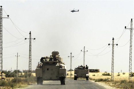 A helicopter flies overhead as soldiers in military vehicles proceed towards al-Jura district in El-Arish city from Sheikh Zuwaid, around 35 A helicopter flies overhead as soldiers in military vehicles proceed towards al-Jura district in El-Arish city from Sheikh Zuwaid, around 35