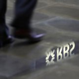 A man walks past a Royal Bank of Scotland branch reflected in a puddle in central London January 14, 2010. REUTERS/Stefan Wermuth