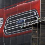 Workers hang a Ford Motor banner on the side of a building across from Cobo Center in advance of the media preview of the North American Int Workers hang a Ford Motor banner on the side of a building across from Cobo Center in advance of the media preview of the North American Int