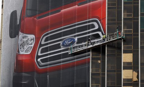 Workers hang a Ford Motor banner on the side of a building across from Cobo Center in advance of the media preview of the North American Int Workers hang a Ford Motor banner on the side of a building across from Cobo Center in advance of the media preview of the North American Int