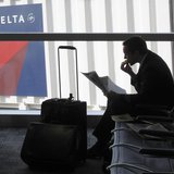A passenger waits for his flight near a Delta Air Lines logo at Detriot Airport November 20, 2010. REUTERS/Sim Wei Yang