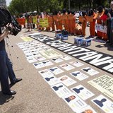 A cameraman films activists wearing orange jumpsuits as they mark the 100th day of prisoners' hunger strike at Guantanamo Bay during a prote A cameraman films activists wearing orange jumpsuits as they mark the 100th day of prisoners' hunger strike at Guantanamo Bay during a prote