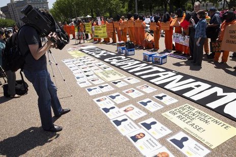 A cameraman films activists wearing orange jumpsuits as they mark the 100th day of prisoners' hunger strike at Guantanamo Bay during a prote A cameraman films activists wearing orange jumpsuits as they mark the 100th day of prisoners' hunger strike at Guantanamo Bay during a prote