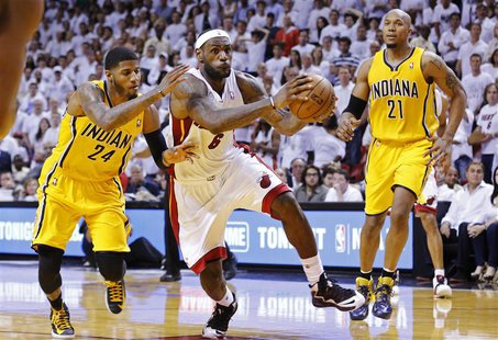 Miami Heat's LeBron James (C) drives through the defense of Indiana Pacers' Paul George (L) and David West on his way to making the game-win Miami Heat's LeBron James (C) drives through the defense of Indiana Pacers' Paul George (L) and David West on his way to making the game-win