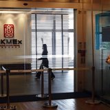 A security guard stands at the entrance as an office worker walks inside the Hong Kong Mercantile Exchange in Hong Kong May 23, 2013. REUTER
