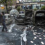 A bystander checks the debris around a row of burnt cars in the suburb of Rinkeby after youths rioted in several different suburbs around St A bystander checks the debris around a row of burnt cars in the suburb of Rinkeby after youths rioted in several different suburbs around St