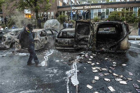 A bystander checks the debris around a row of burnt cars in the suburb of Rinkeby after youths rioted in several different suburbs around St A bystander checks the debris around a row of burnt cars in the suburb of Rinkeby after youths rioted in several different suburbs around St