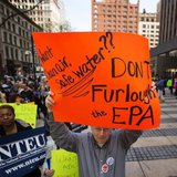 A federal employee holds up a sign protesting the effects of sequestration and the practice of furloughs at a gathering in New York, May 7, 