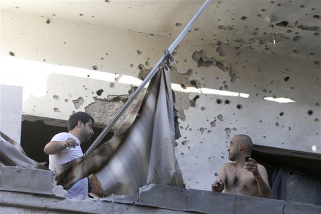 Two men inspect their damage house after two rockets hit their area in a Beirut suburbs May 26, 2013. Two rockets hit a Hezbollah-controlled Two men inspect their damage house after two rockets hit their area in a Beirut suburbs May 26, 2013. Two rockets hit a Hezbollah-controlled