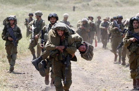 An Israeli soldier carries another soldier as they walk with their comrades during training close to the ceasefire line between Israel and S An Israeli soldier carries another soldier as they walk with their comrades during training close to the ceasefire line between Israel and S