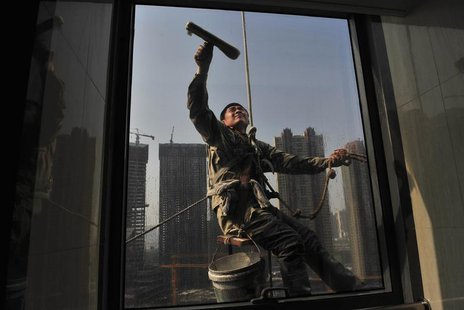 A labourer cleans the window of an office building near a residential complex (back) under construction in Shenyang, Liaoning province May 1 A labourer cleans the window of an office building near a residential complex (back) under construction in Shenyang, Liaoning province May 1