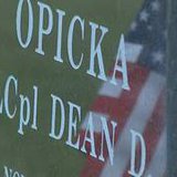 An American flag is reflected on the headstone of Marine Lance Corporal Dean Opicka of Casco on Sunday, May 26, 2013. LCpl. Opicka died in Iraq in 2008. (courtesy of FOX 11).