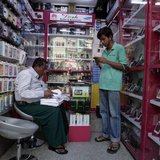 A man selling mobile phones, uses his own at a shop in Yangon February 4, 2013. REUTERS/Soe Zeya Tun