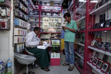 A man selling mobile phones, uses his own at a shop in Yangon February 4, 2013. REUTERS/Soe Zeya Tun A man selling mobile phones, uses his own at a shop in Yangon February 4, 2013. REUTERS/Soe Zeya Tun