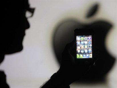 A man is silhouetted against a video screen with an Apple logo as he poses with an Apple iPhone 4 smartphone in this photo illustration take A man is silhouetted against a video screen with an Apple logo as he poses with an Apple iPhone 4 smartphone in this photo illustration take