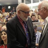 British physicist Peter Higgs (R) shakes hands with Belgium physicist Francois Englert before a scientific seminar to deliver the latest upd