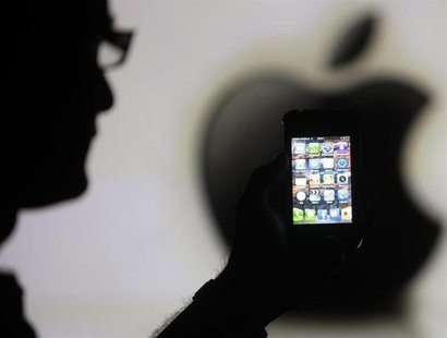 A man is silhouetted against a video screen with an Apple logo as he poses with an Apple iPhone 4 smartphone in this photo illustration take A man is silhouetted against a video screen with an Apple logo as he poses with an Apple iPhone 4 smartphone in this photo illustration take