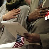 Immigrants put their hands to their hearts as the national anthem is played during a special naturalization ceremony at the Department of Ju