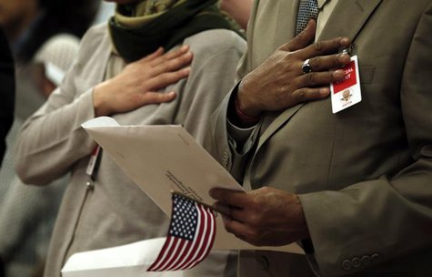 Immigrants put their hands to their hearts as the national anthem is played during a special naturalization ceremony at the Department of Ju Immigrants put their hands to their hearts as the national anthem is played during a special naturalization ceremony at the Department of Ju
