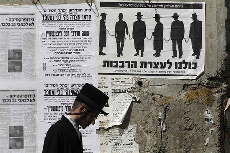 An ultra-Orthodox Jewish man walks past a street poster in Jerusalem's Mea Shearim neighbourhood, inviting the public to a protest against g An ultra-Orthodox Jewish man walks past a street poster in Jerusalem's Mea Shearim neighbourhood, inviting the public to a protest against g