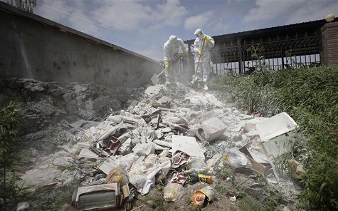 Health officers sterilize a dump site with lime powder, near the site of a poultry slaughterhouse fire in Dehui, Jilin province June 6, 2013 Health officers sterilize a dump site with lime powder, near the site of a poultry slaughterhouse fire in Dehui, Jilin province June 6, 2013