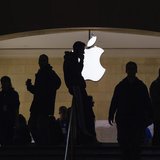 A man talks on his telephone as customers walk through an Apple store in Grand Central Terminal in New York, March 15, 2013. REUTERS/Lucas J