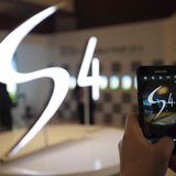 A man takes a photograph of a logo of Samsung Electronics Co Ltd's latest flagship smartphone S4 during its launch event at the company's he