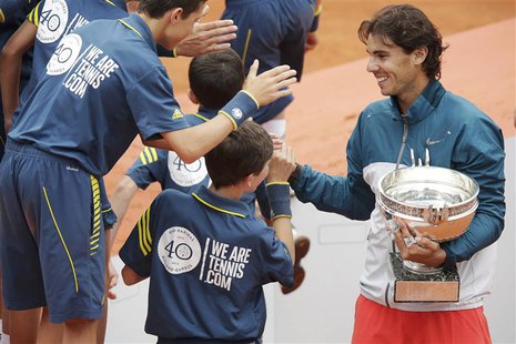 Rafael Nadal of Spain holds his trophy as he shakes hands with ball boys after defeating compatriot David Ferrer in their men's singles fina Rafael Nadal of Spain holds his trophy as he shakes hands with ball boys after defeating compatriot David Ferrer in their men's singles fina