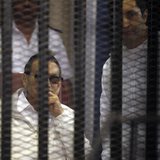 Egypt's ousted President Hosni Mubarak (L) sits near his son Alaa behind bars during their trial inside a dock at the police academy, on the