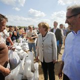 German Chancellor Angela Merkel and Brandenburg State Premier Matthias Platzeck (R) meet volunteers reinforcing a dyke at the bank of the ri