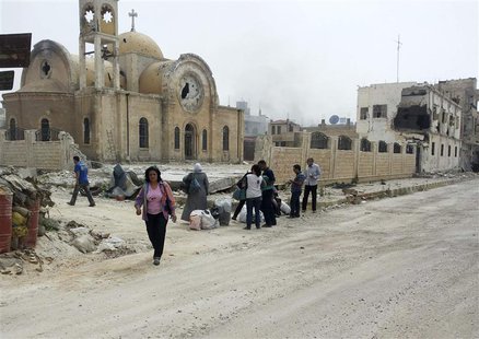 Residents walk near a damaged church as they are seen in Qusair to inspect their houses and collect their belongings June 8, 2013. REUTERS/R Residents walk near a damaged church as they are seen in Qusair to inspect their houses and collect their belongings June 8, 2013. REUTERS/R
