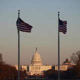 Flags at the Washington Monument flutter in the breeze as the sun casts its last rays on the U.S. Capitol Building in Washington February 5,