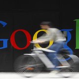 An employee rides her bike past a logo next to the main entrance of the Google building in Zurich July 9, 2009. REUTERS/Christian Hartmann
