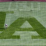 A Los Angeles Dodgers grounds crewman sweeps away the dew from the centerfield grass to prepare the field to play against the San Francisco 