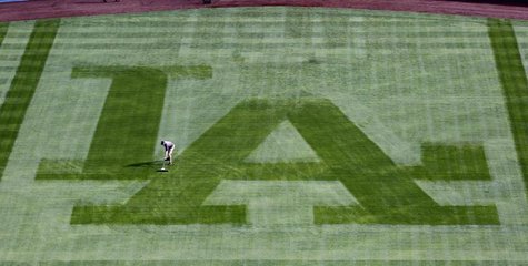 A Los Angeles Dodgers grounds crewman sweeps away the dew from the centerfield grass to prepare the field to play against the San Francisco A Los Angeles Dodgers grounds crewman sweeps away the dew from the centerfield grass to prepare the field to play against the San Francisco
