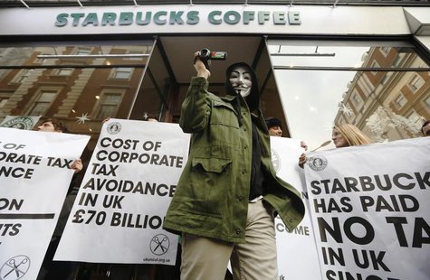 A masked demonstrator leaves a Starbucks coffee shop in central London December 8, 2012. REUTERS/Luke MacGregor A masked demonstrator leaves a Starbucks coffee shop in central London December 8, 2012. REUTERS/Luke MacGregor