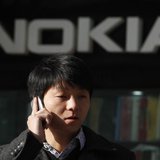 A man using his mobile phone walks under a Nokia logo in Shanghai December 6, 2012. REUTERS/Aly Song