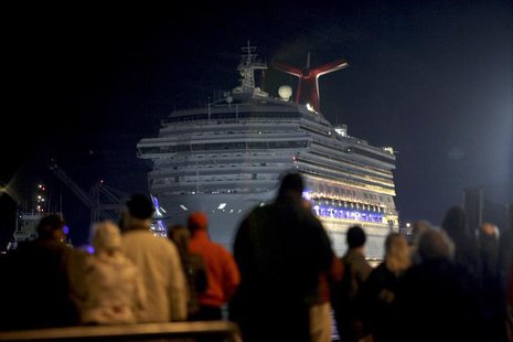 The Carnival Triumph cruise ship is towed towards the dock as spectators watch at the port of Mobile, Alabama, February 14, 2013. REUTERS/ L The Carnival Triumph cruise ship is towed towards the dock as spectators watch at the port of Mobile, Alabama, February 14, 2013. REUTERS/ L
