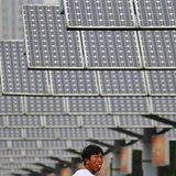 A man eats his breakfast as he walks under solar panels belonging to a solar power plant in Shenyang, Liaoning province June 5, 2013. REUTER