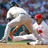 Los Angeles Angels shortstop Erick Aybar (R) takes a seat as the throw from the catcher takes him away from second base with New York Yankee