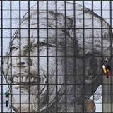Rope access technicians work to complete a huge portrait of former South African President Nelson Mandela on the windows of the Civic Centre