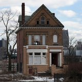 A vacant, boarded up house is seen in the once thriving Brush Park neighborhood with the downtown Detroit skyline behind it in Detroit, Mich