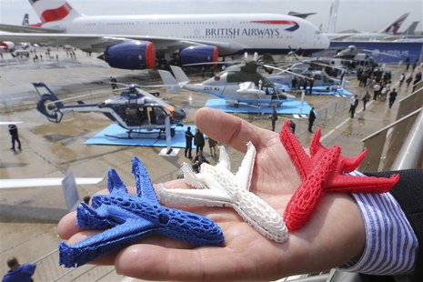 An Airbus employee presents three model airplanes in blue, white and red, made from starch using a 3D printing technique during the opening An Airbus employee presents three model airplanes in blue, white and red, made from starch using a 3D printing technique during the opening