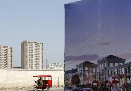 A tricycle drives past an large advertisement board of a new apartment complex at a new residential town in Beijing February 27, 2013. REUTE A tricycle drives past an large advertisement board of a new apartment complex at a new residential town in Beijing February 27, 2013. REUTE