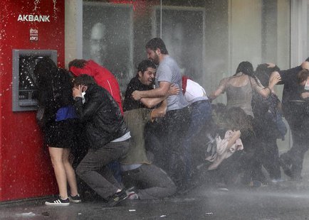 Anti-government protesters try to protect themselves from a water cannon as riot police disperse them during a protest in Ankara June 5, 201 Anti-government protesters try to protect themselves from a water cannon as riot police disperse them during a protest in Ankara June 5, 201
